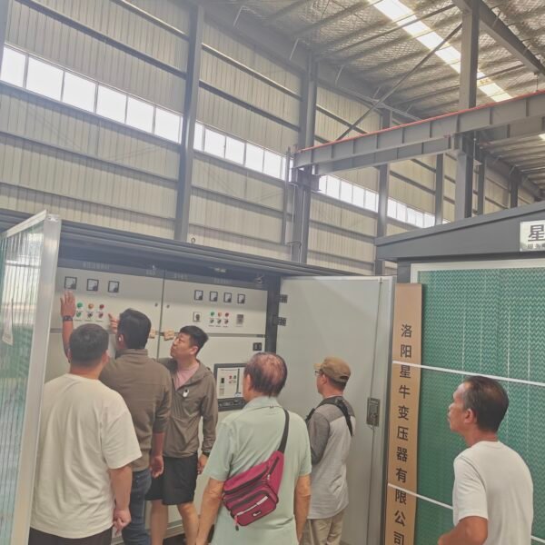 Customers inspecting an electrical control cabinet during an XNET transformer factory tour